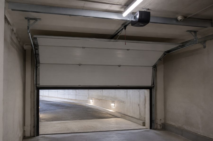 Puerta seccional de garaje abierta con el motor y las guías instalados en el techo
